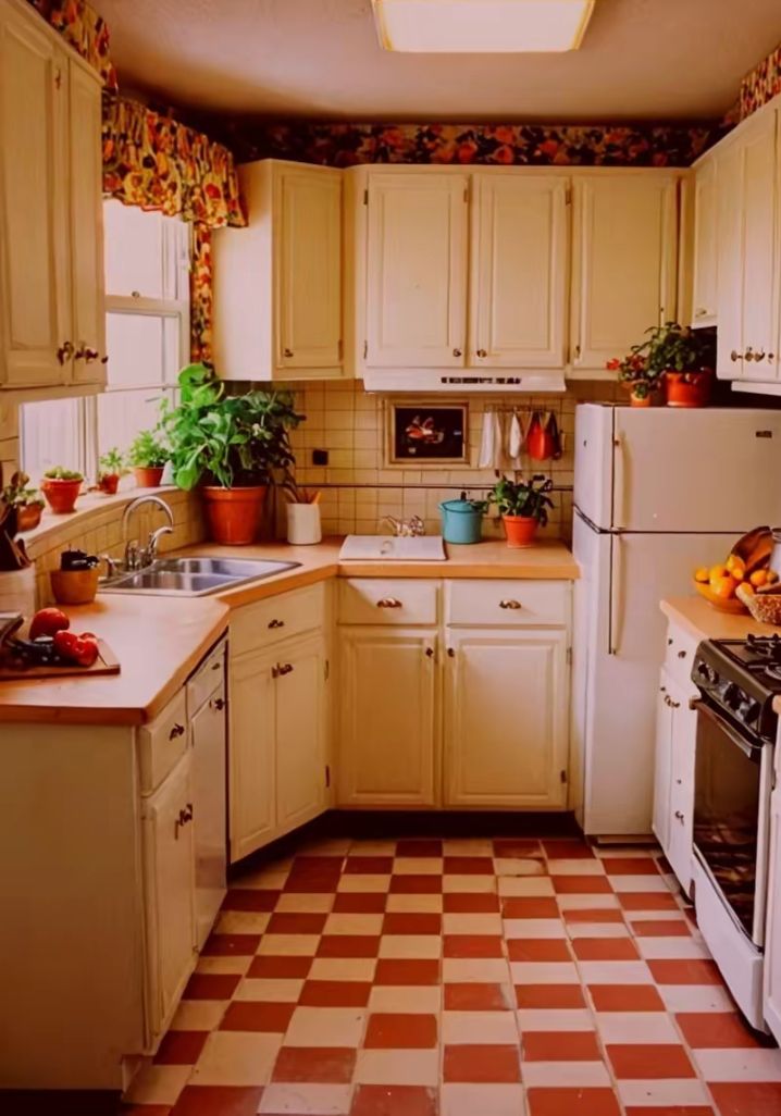 a kitchen filled with white appliances and lots of counter space next to a window covered in potted plants