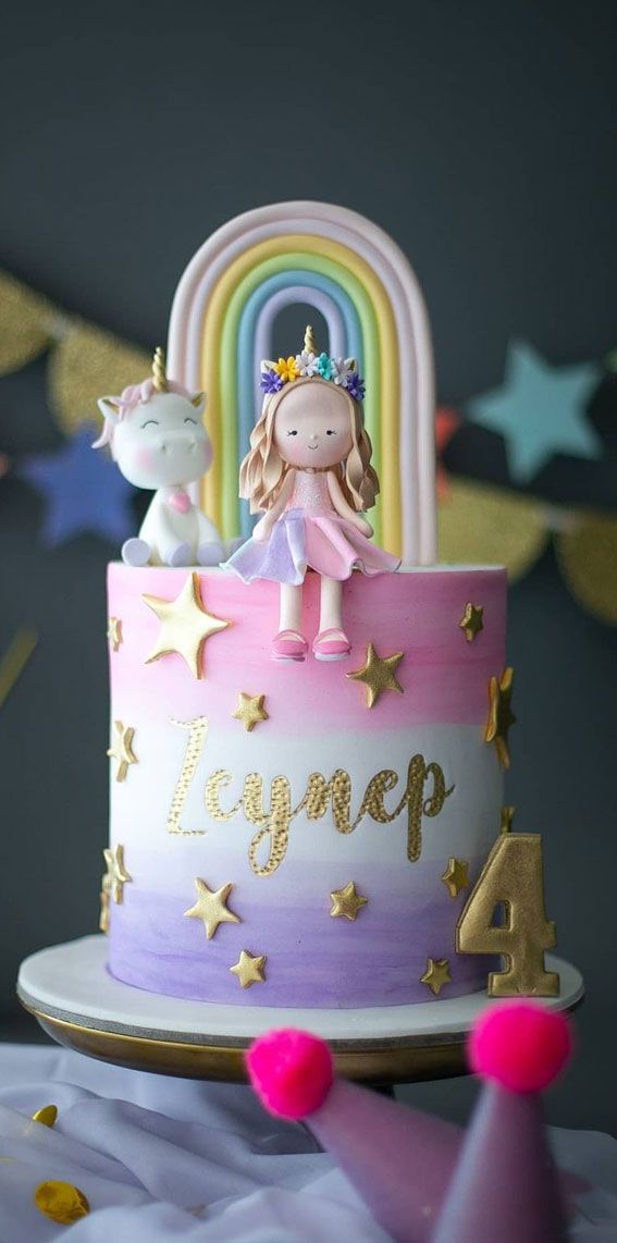 a birthday cake decorated with unicorns and stars on the top is pink, purple, yellow and white