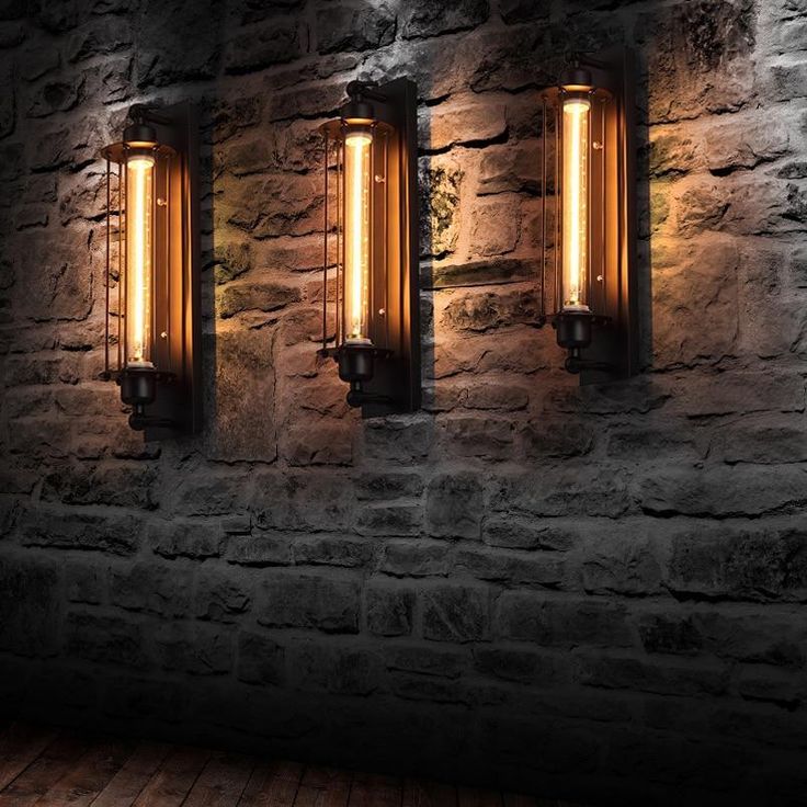 three lights are lit up on the side of a brick wall