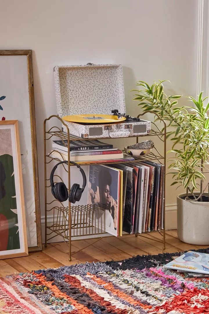 a record player sits on top of a metal stand next to a potted plant