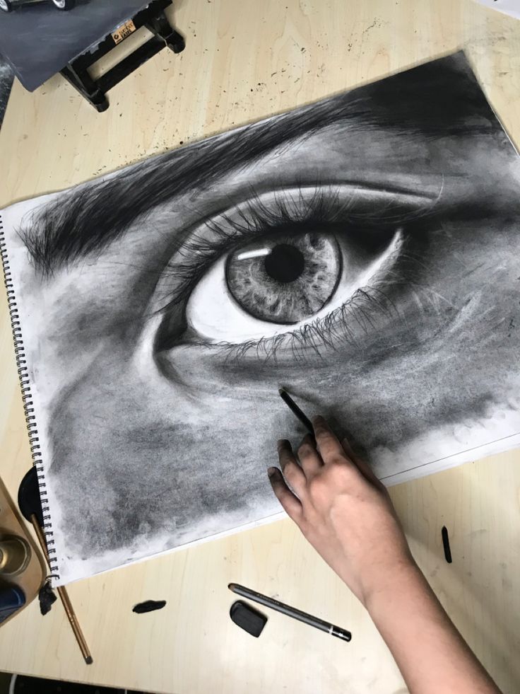 someone is drawing an eye with pencils on a table next to some other items