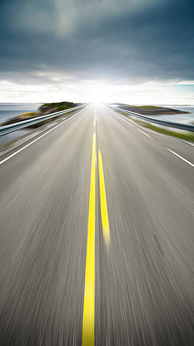 an empty road with yellow lines going through the center and dark clouds in the background