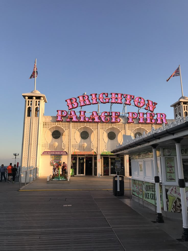 an amusement park with large neon signs on the building and people walking around in front