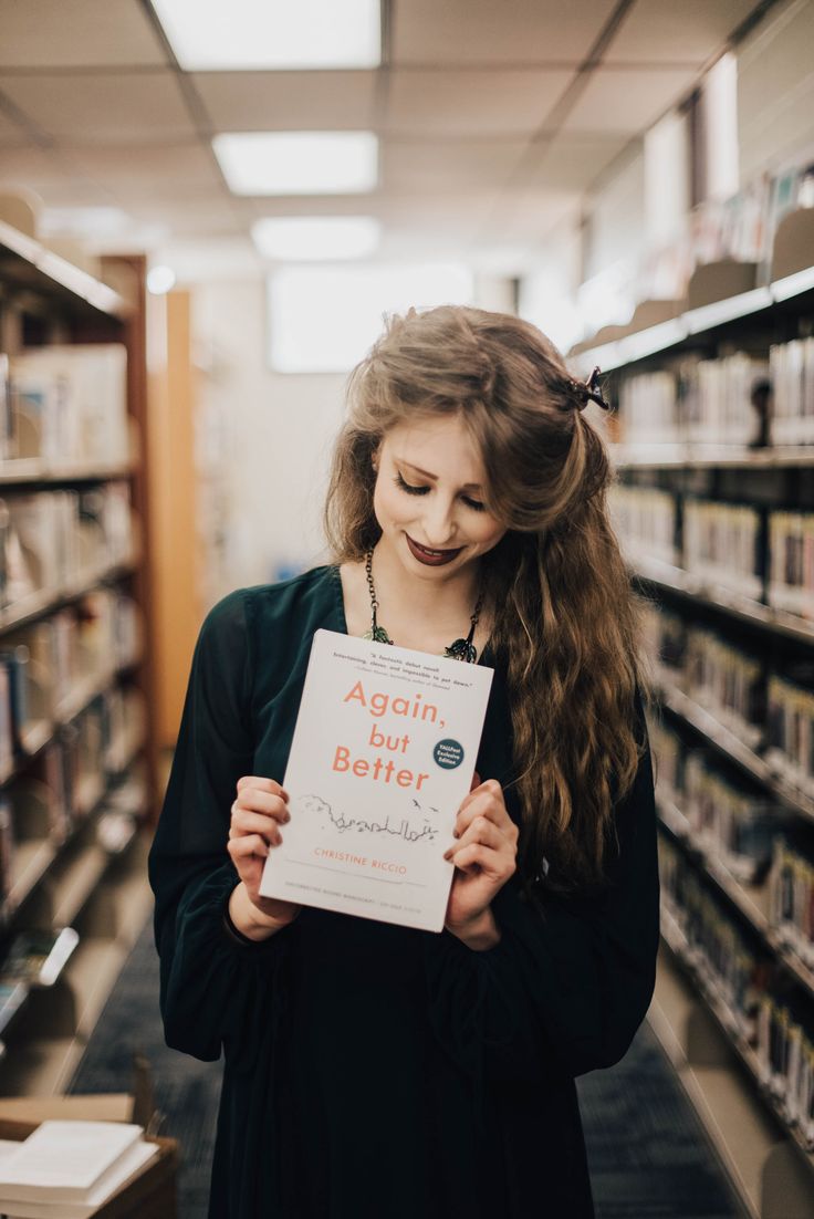 a woman holding up a book in a library