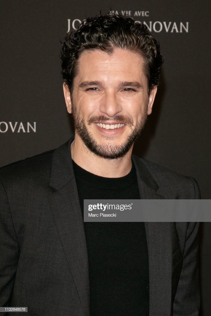 a smiling man in a suit and black shirt poses for the camera at an event