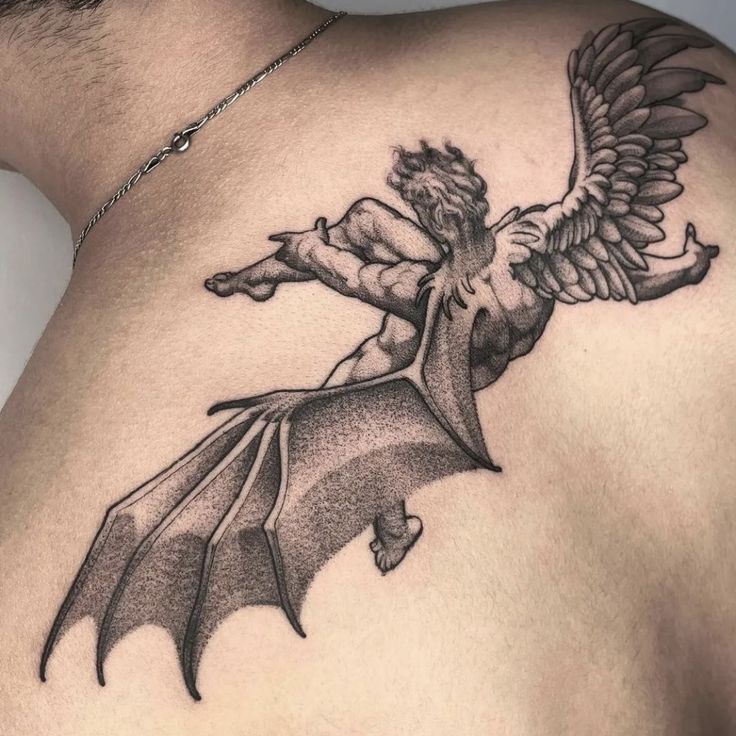 the back of a man's shoulder with an angel and demon tattoo on it