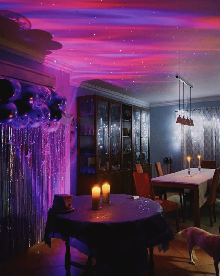 a dining room filled with purple lights and balloons on the ceiling next to a table