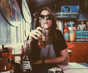 a woman sitting at a table with a beer in her hand