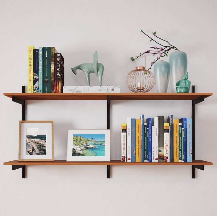 two wooden shelves with books, vases and pictures on them against a white wall