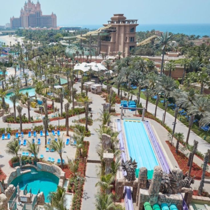 an aerial view of a resort with pool and water slides in the middle, surrounded by palm trees