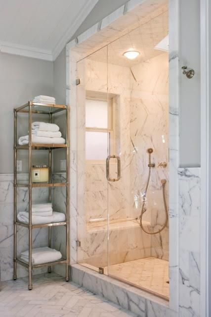 a walk in shower sitting next to a bath tub filled with lots of white towels