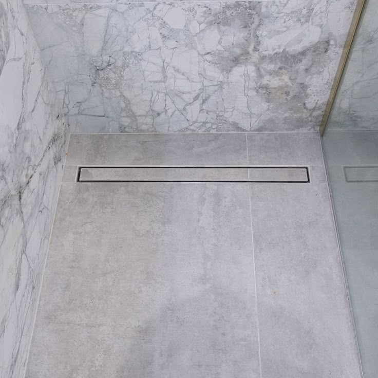 a bathroom with marble walls and flooring in the shower area is seen from above