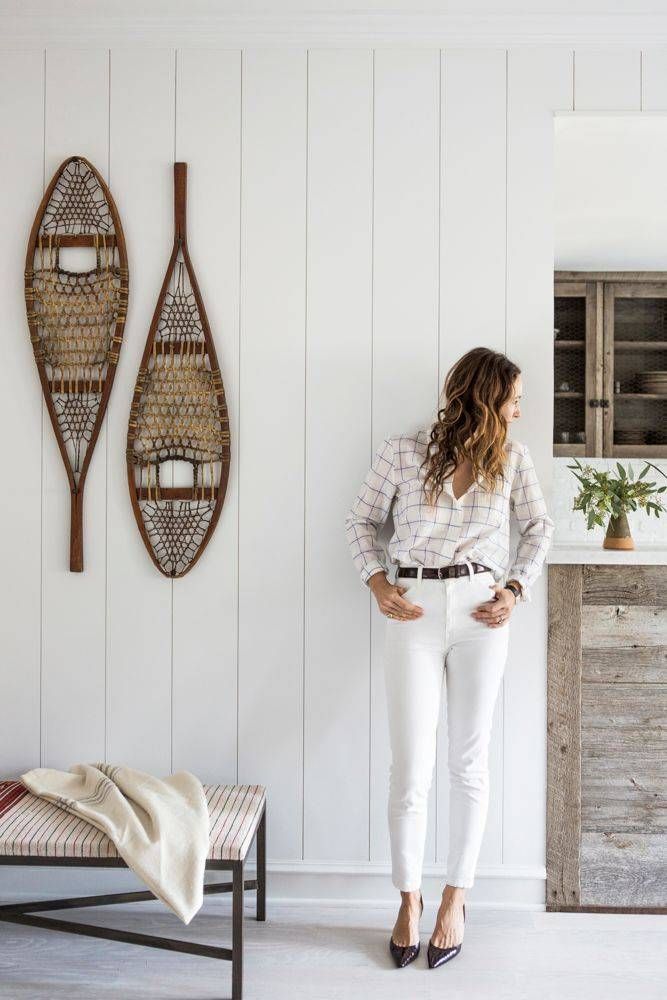 a woman standing in front of a wall with two canoes hanging on the wall