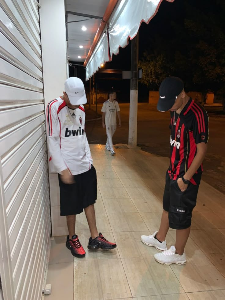 two young men standing next to each other in front of a garage door at night