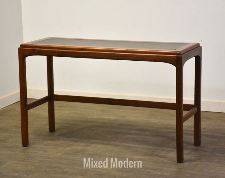 a wooden table sitting on top of a hard wood floor next to a white wall