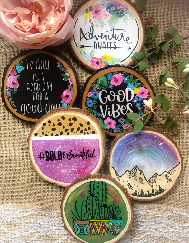 six decorated cookies sitting on top of a table next to pink flowers and greenery