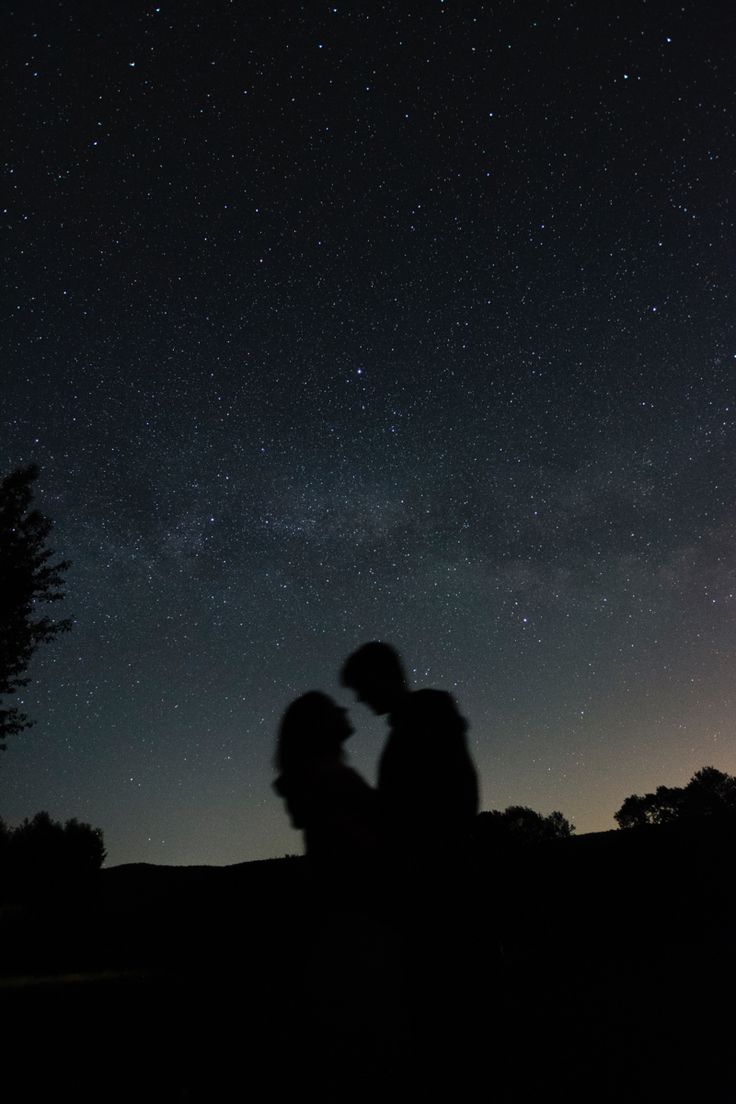 two people are standing under the stars in the sky