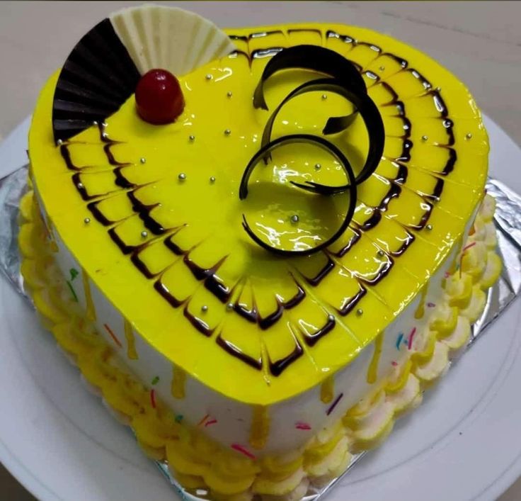 a yellow and white cake with chocolate decorations on it's top, sitting on a plate