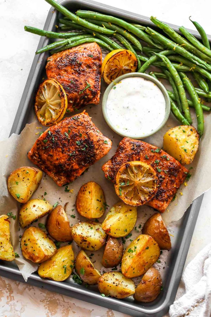 salmon, potatoes and asparagus on a tray with ranch dressing next to it