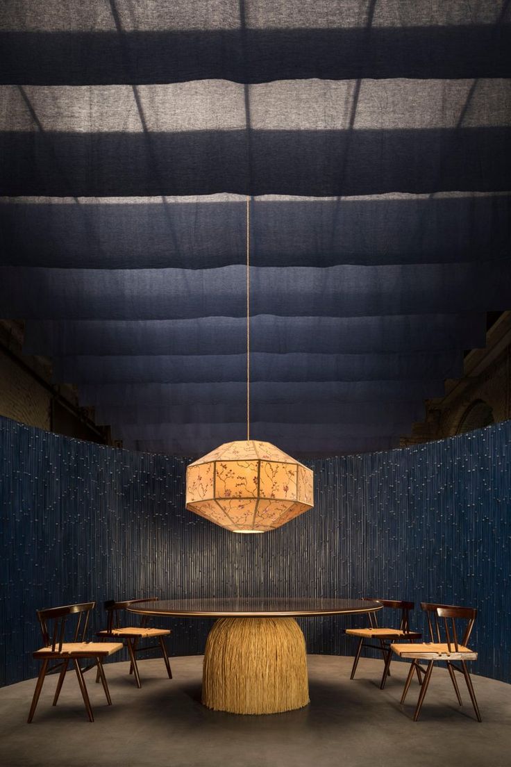 a round table with four chairs and a chandelier hanging from it's ceiling