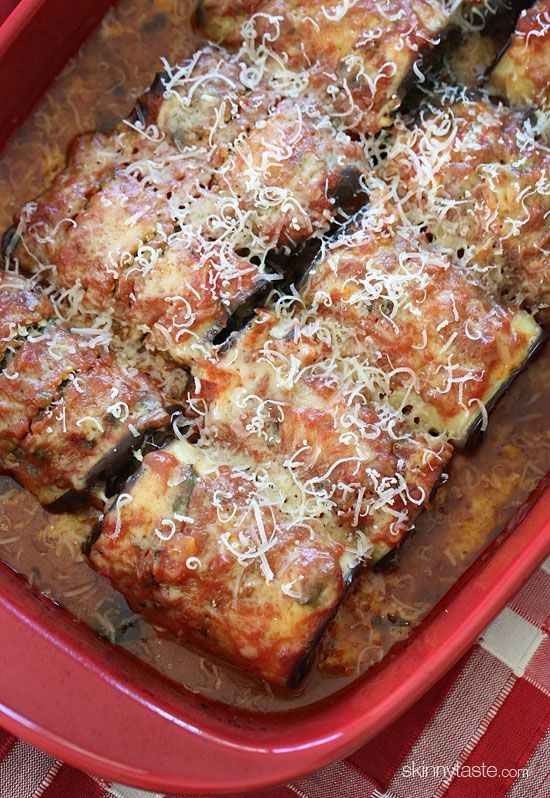 a red casserole dish with meat and cheese on top, sitting on a checkered table cloth