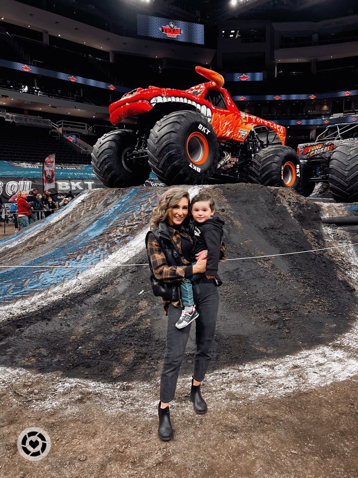 a woman and child standing in front of a monster truck