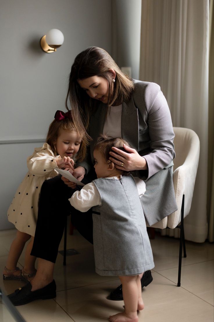 a woman sitting next to two small children