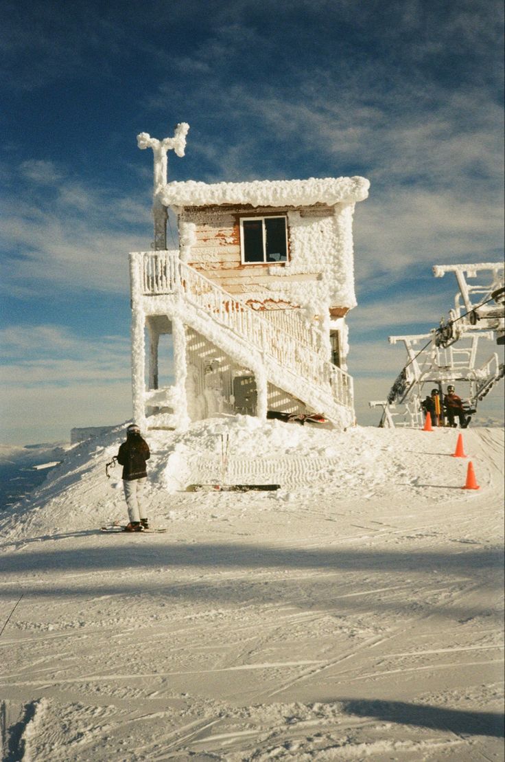 a person on skis standing in front of a house covered in snow and ice