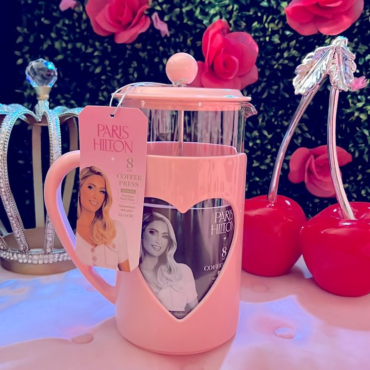 a pink coffee mug sitting on top of a table next to two red roses and other items