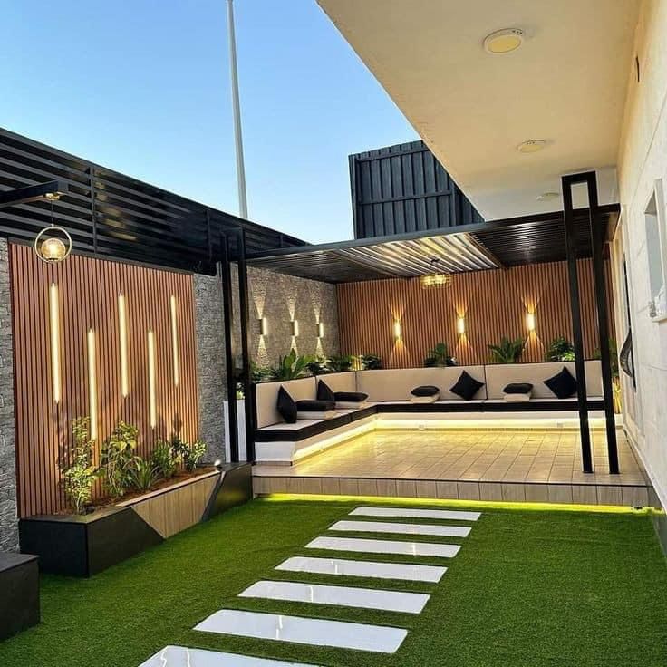 an outdoor living area with grass and steps leading up to the roof top deck, surrounded by modern lighting