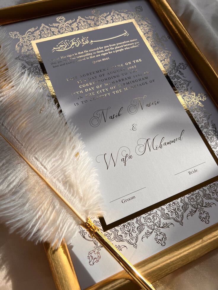 the wedding stationery is in gold and silver with a white feather on it's tail