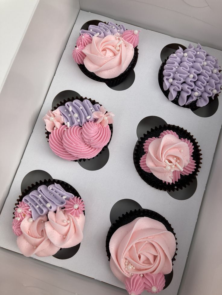 six cupcakes with pink and purple frosting in a box