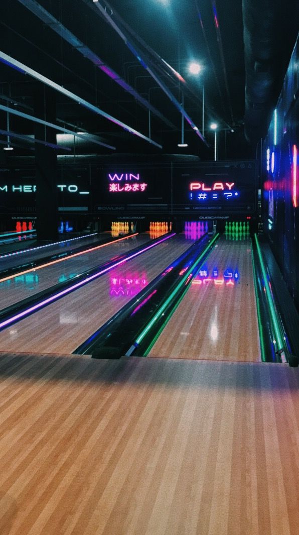 a bowling alley with neon lights on the floor and bowling pins in the lanes behind it