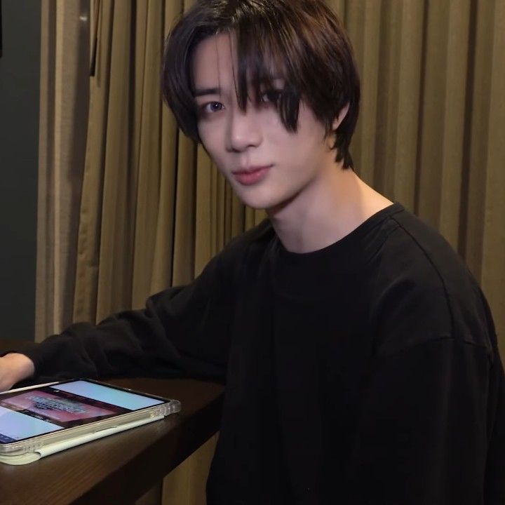 a young man sitting at a table with an ipad