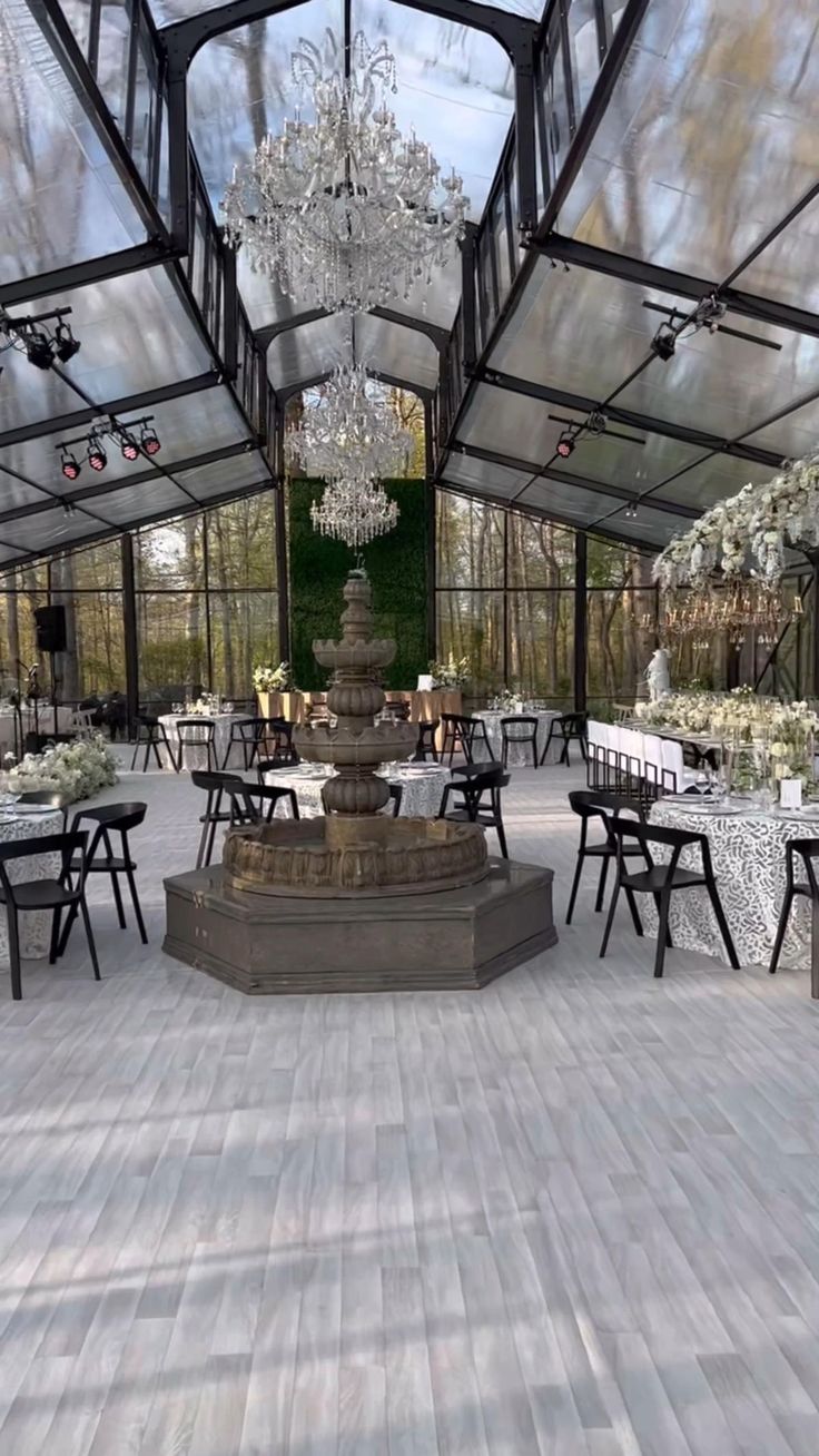 an outdoor dining area with tables, chairs and chandelier in the middle of it