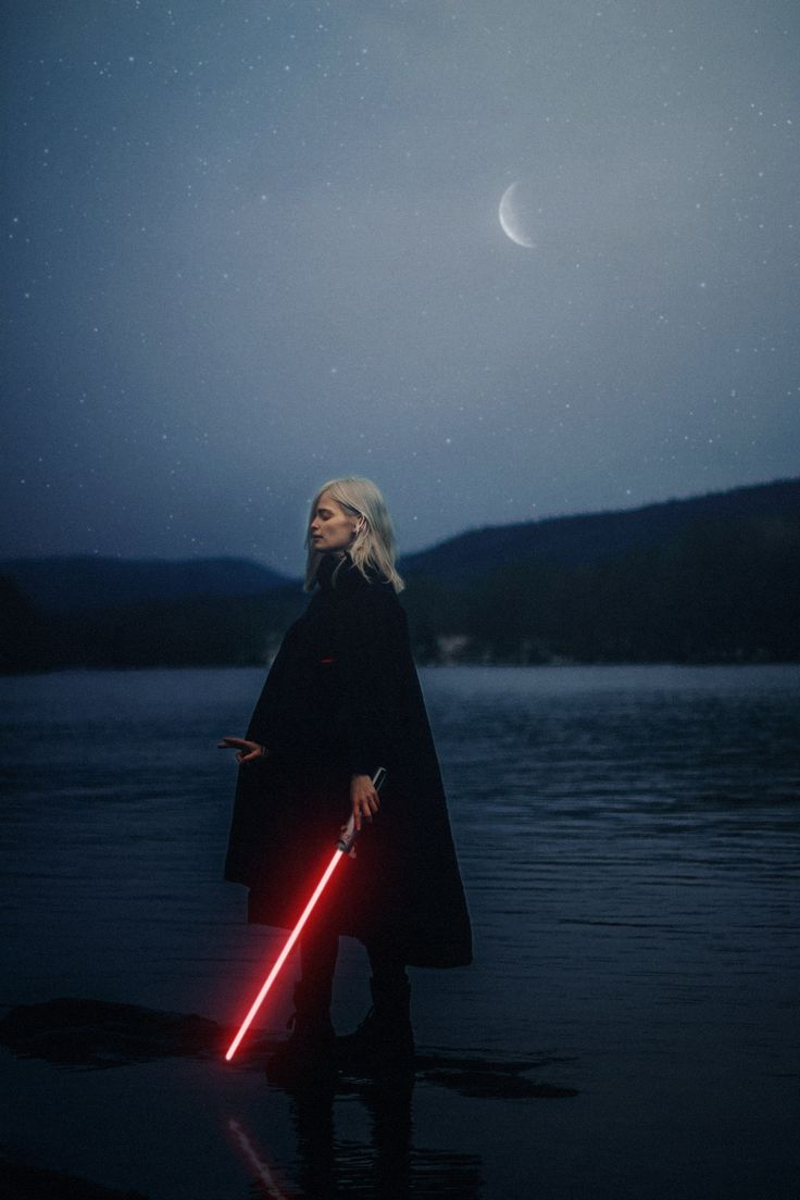 a woman standing in the water holding a light saber