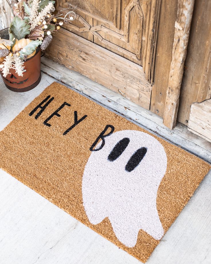 a door mat that says hey boo on it with a ghost face in the center