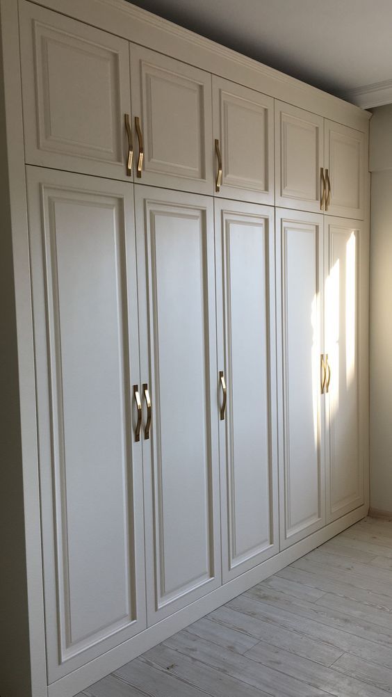 an empty room with white cabinets and wood floors