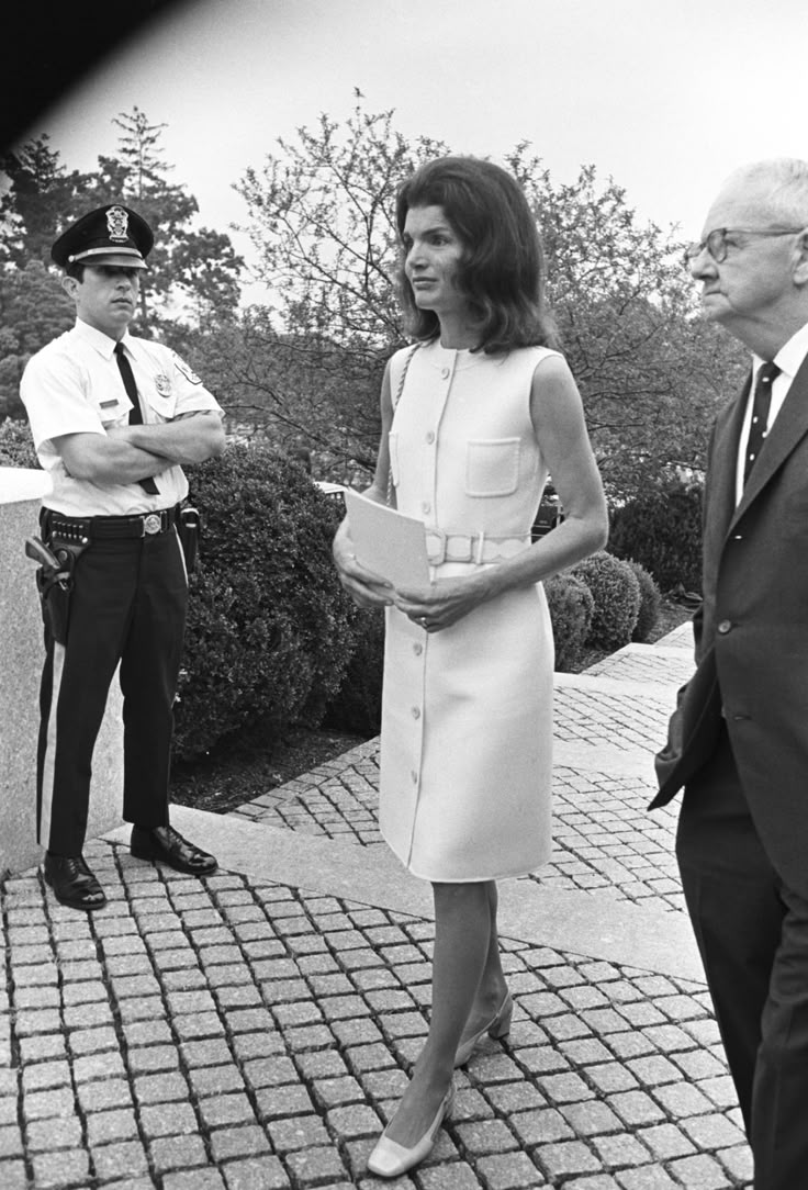 a woman in a white dress standing next to two men