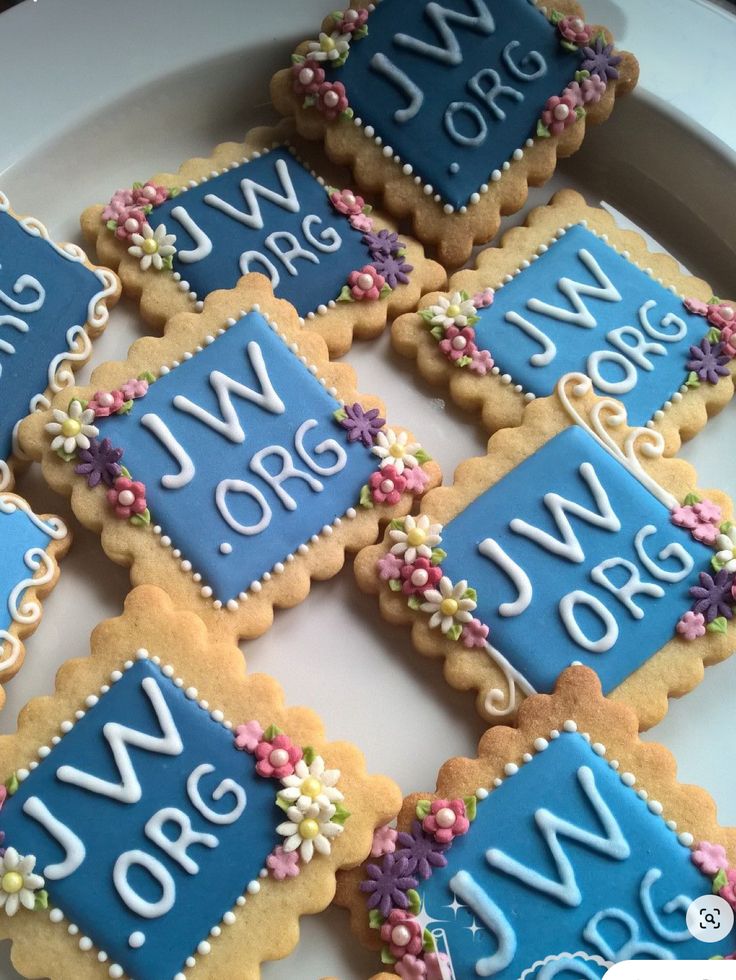 decorated cookies are arranged on a plate with letters and numbers written in blue icing