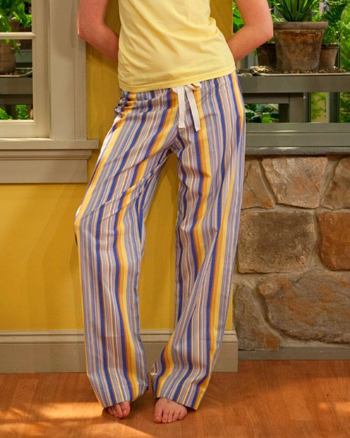 a woman standing in front of a window wearing striped pants