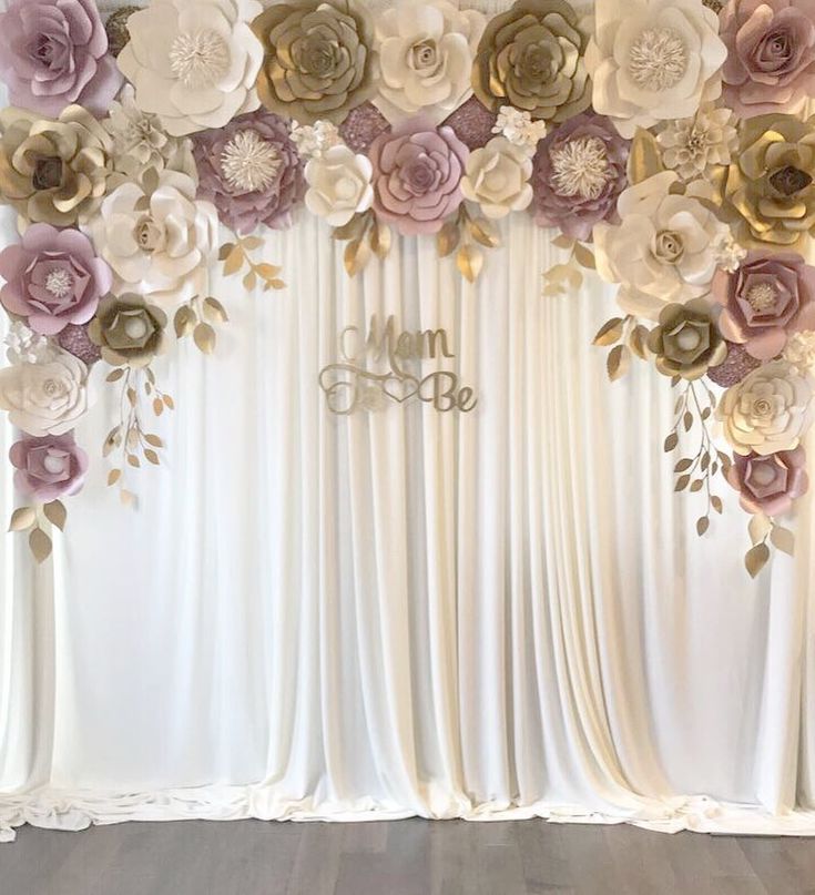 the backdrop is decorated with paper flowers and gold leaf accents, along with monogrammed initials