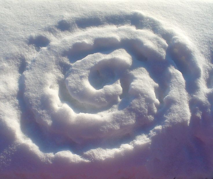 a snow covered ground with a spiral design in the middle