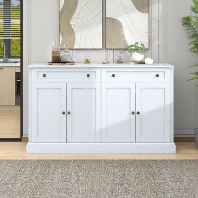 a white sideboard with two mirrors on the wall and a potted plant next to it