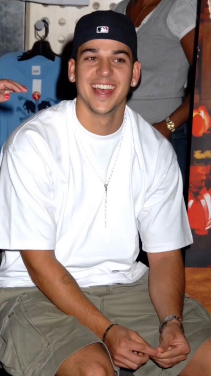 a young man sitting on the ground smiling