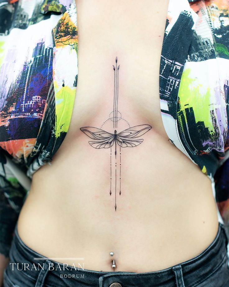 a woman's lower back tattoo with a dragonfly on her stomach and an arrow in the middle