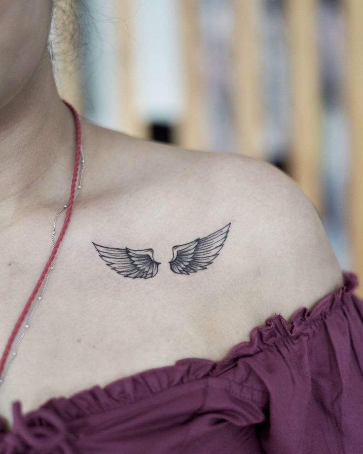 a woman's chest with two wings tattoo on her left shoulder and right arm