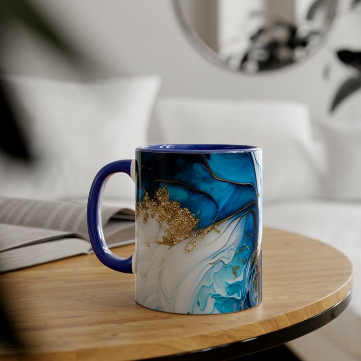 a blue and white coffee mug sitting on top of a table next to a book