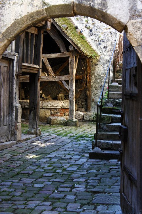 an old stone building with stairs leading up to the door and into it is a brick walkway