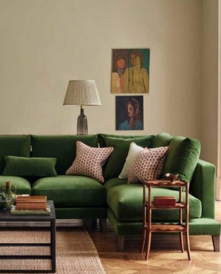 a living room filled with green couches and pillows on top of a hard wood floor